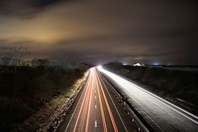 Light trails on road against sky at night