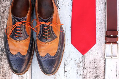 Directly above view of leather shoes with necktie and belt on floorboard