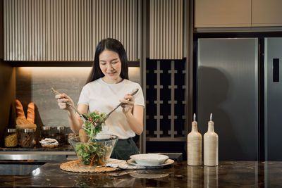 Young woman holding ice cream in kitchen