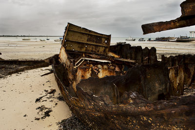 Abandoned boat on beach against sky