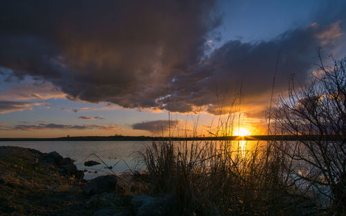 Scenic view of sea against cloudy sky at sunset