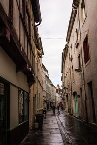 Alley amidst street in city against sky