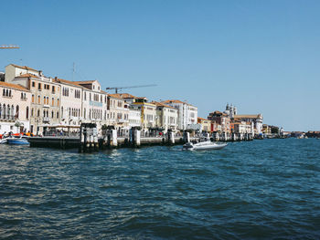 Canal against buildings in city on sunny day