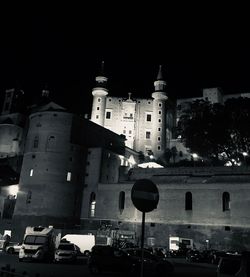 Cars on road by buildings against sky in city at night