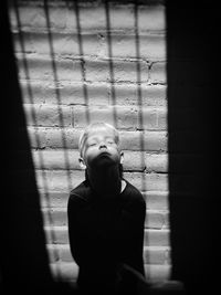 Sunlight falling on boy standing against wall