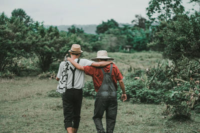 Rear view of friends walking on street amidst trees