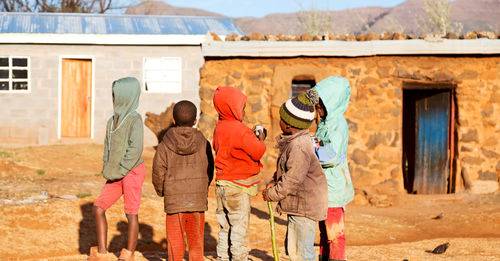 Rear view of people standing against built structure