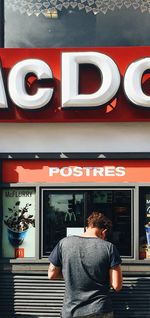 Rear view of man standing at illuminated restaurant