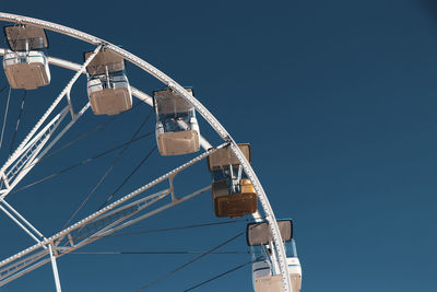 Low angle view of ferris wheel against clear blue sky