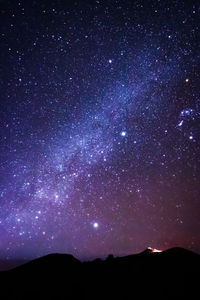 Low angle view of silhouette mountain against star field