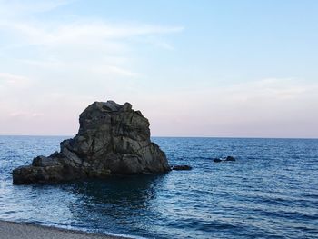 Rock formation in sea against sky