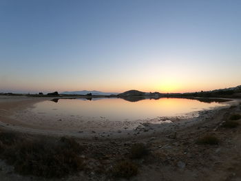 Scenic view of beach against clear sky during sunset