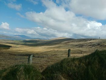 Scenic view of grassy field against cloudy sky