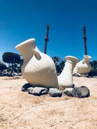 Statues on land against clear blue sky