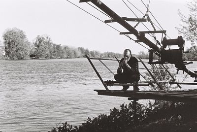 Full length of young woman sitting on tree against sky