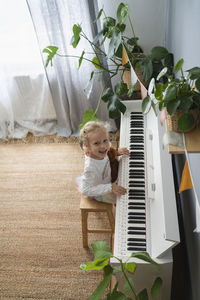 Happy girl playing piano amidst plants at home