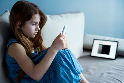 Side view of woman using mobile phone at home