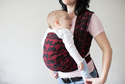 Midsection of woman carrying baby in harness