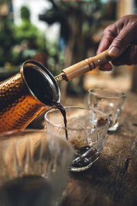 Close-up of hand pouring drink in glass on table