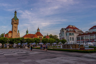 People in front of buildings against sky in city