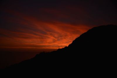 Scenic view of silhouette mountains against orange sky