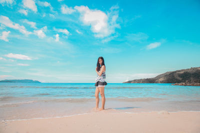 Full length of woman standing at beach against sky