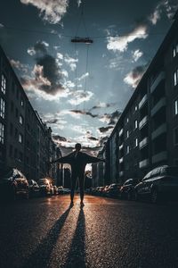Rear view of woman standing on road in city against sky