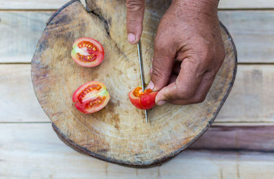 High angle view of hands cutting tomatoes