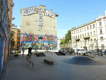 People at skateboard park against graffiti wall in city