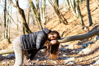 Young woman climbing a fallen tree