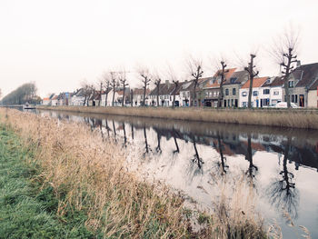 Houses by river against sky during winter