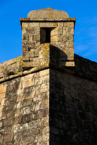 Low angle view of stone wall against blue sky