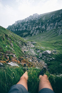 Low section of person on mountain against sky