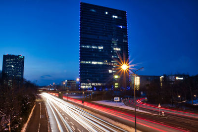 High angle view of light trails on road at night with building 