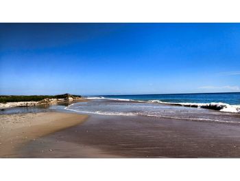 Scenic view of beach against clear blue sky
