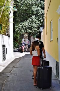 Rear view of women walking on street amidst buildings