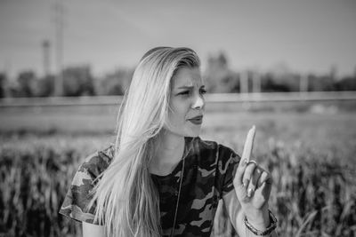 Young woman looking away while standing on field