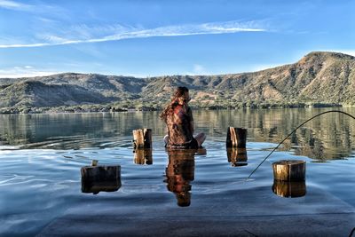 Woman sitting amidst lake on wood