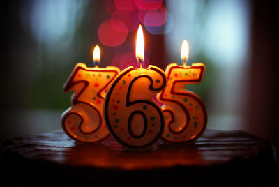 Illuminated candles with numbers on cake