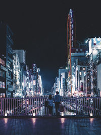 Rear view of illuminated buildings against sky at night