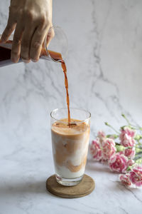 Milk tea. pouring milk from jar to a cup of ice tea or coffee. ice tea with carnation.