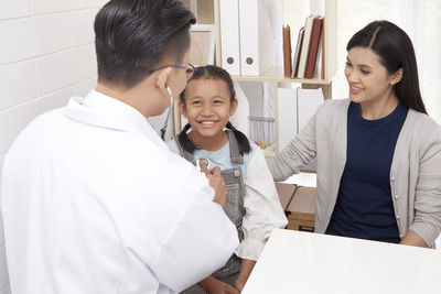 Mother looking at doctor examining girl in clinic