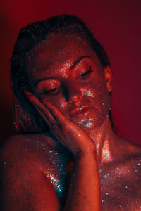 Close-up of shirtless young woman with glitters in darkroom