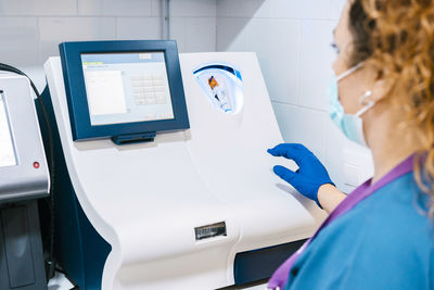 Mature nurse analyzing blood sample through machinery at laboratory
