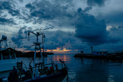 Sailboats moored in sea against sky at dusk