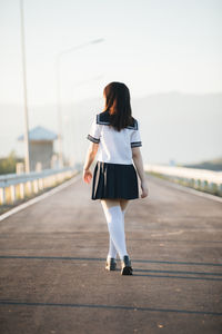 Rear view of woman walking on road against sky