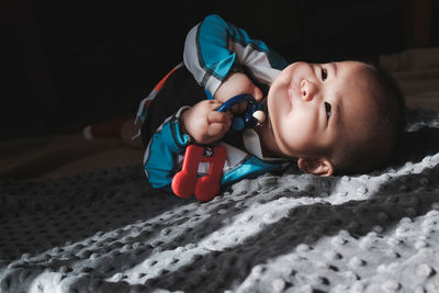 Cute boy with toy lying on bed