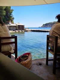 Man relaxing on table by sea against clear sky