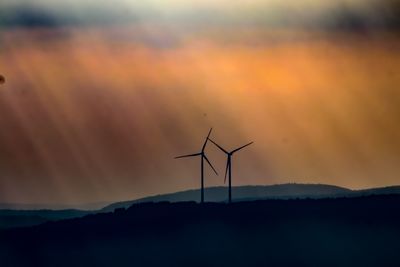 Silhouette wind turbine against sky during sunset