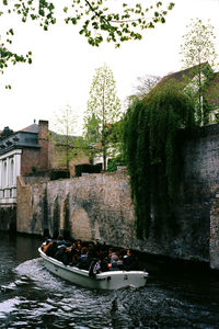 Boats in river by buildings against sky